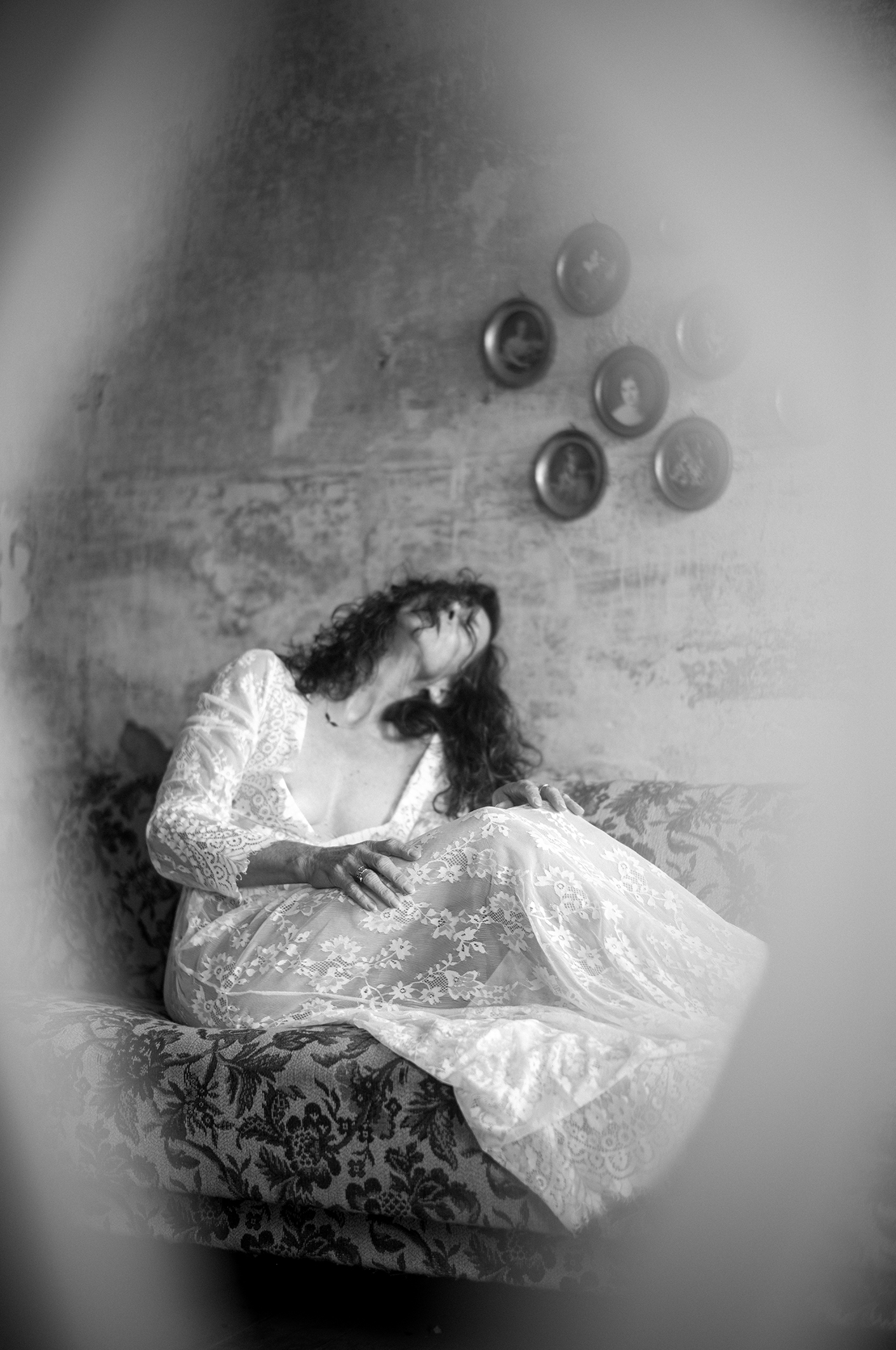 Frau in weißem Spitzenkleid auf einem Sofa – Schwarz-Weiß-Fotografie von Bernhard Brause